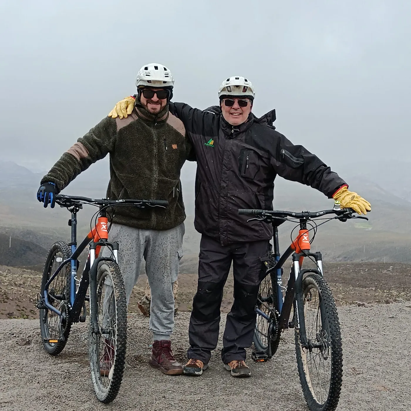 Ciclistas abrazados en la cumbre, altiplano entre la niebla
