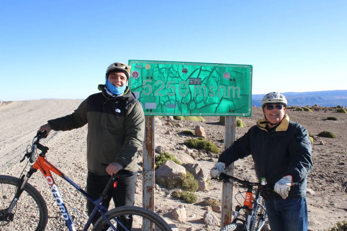 Dos ciclistas con sus bicicletas junto al letrero de los 5.250 m.s.n.m.